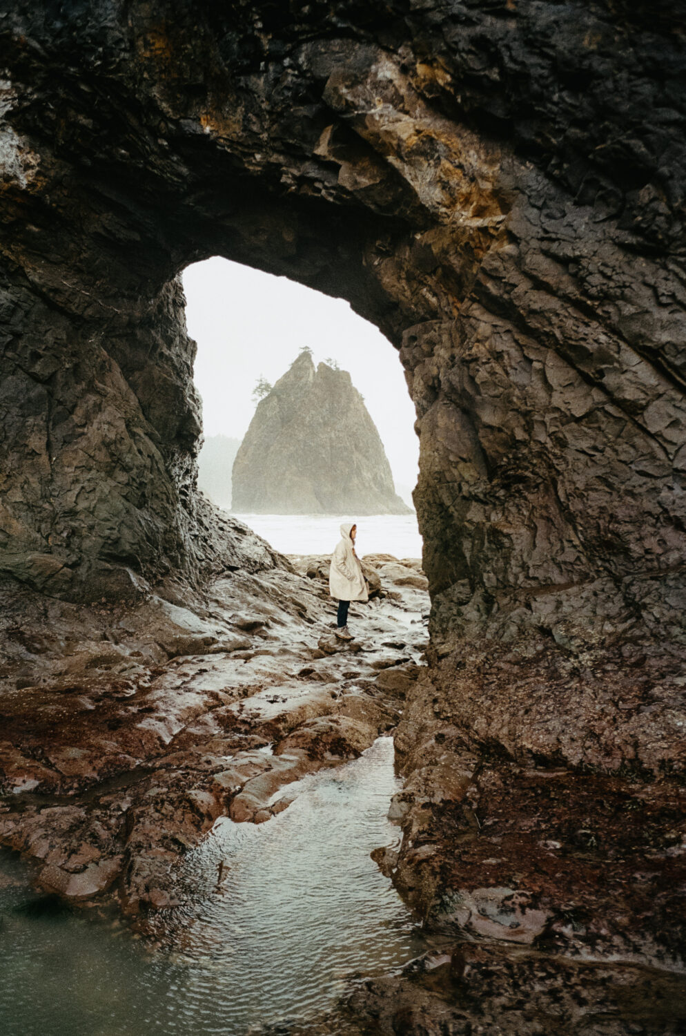 Emily Mandagie se para en el agujero en la pared, Rialto Beach TEMPORADA DE INVIERNO - TheMandagies.com