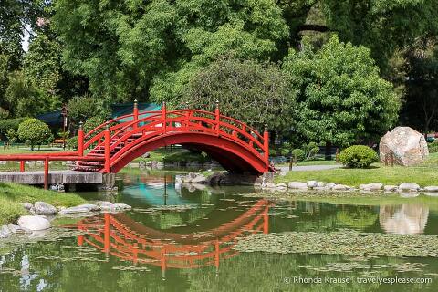 Puente de arco rojo que cruza el estanque.