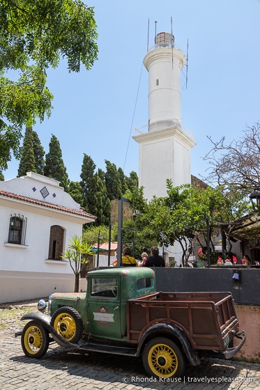 Camioneta antigua estacionada frente al faro de Colonia del Sacramento.