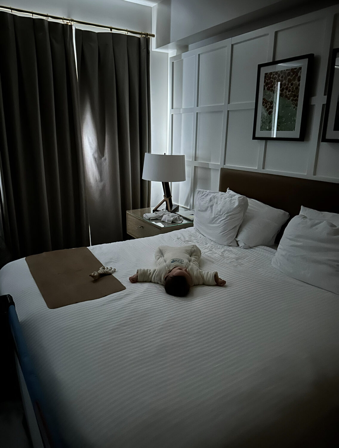 El bebé duerme supervisado en la cama del hotel.